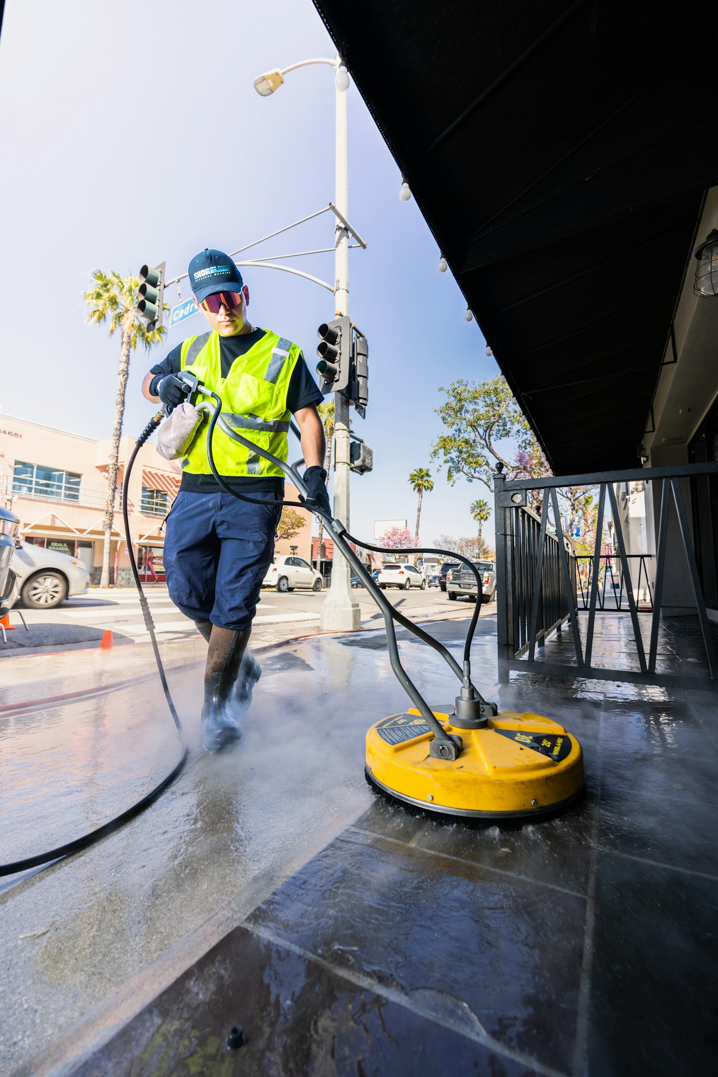 Palmetto Pressure Pros technician running a surface cleaner on a storefront sidewalk